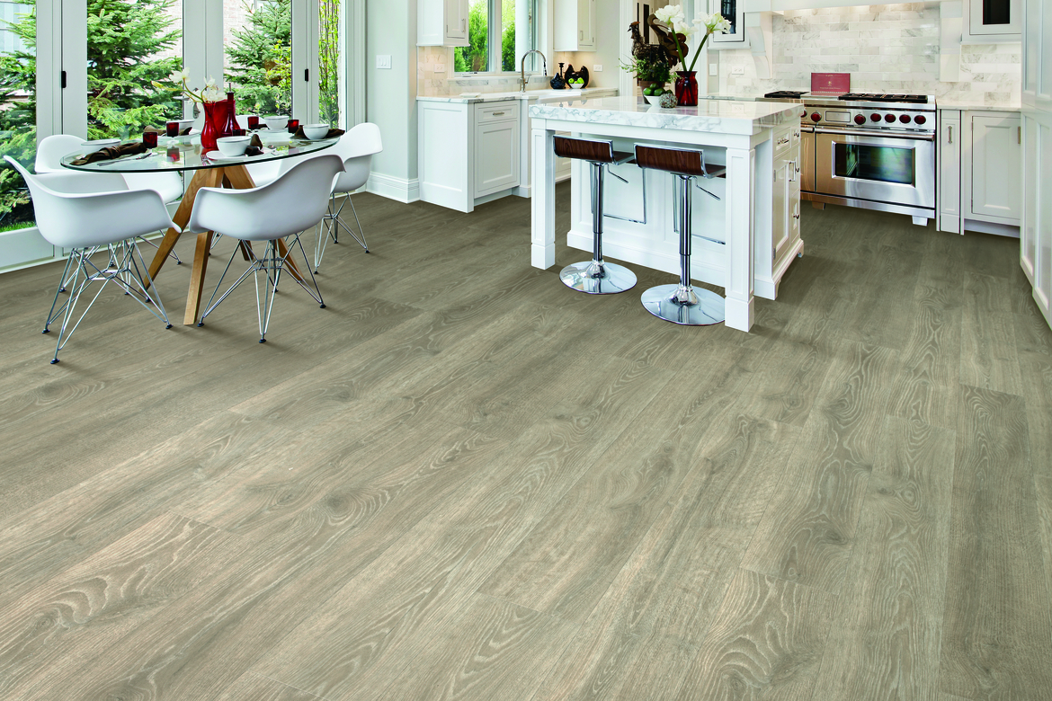 Laminate flooring in a kitchen with a dining table and white cabinetry